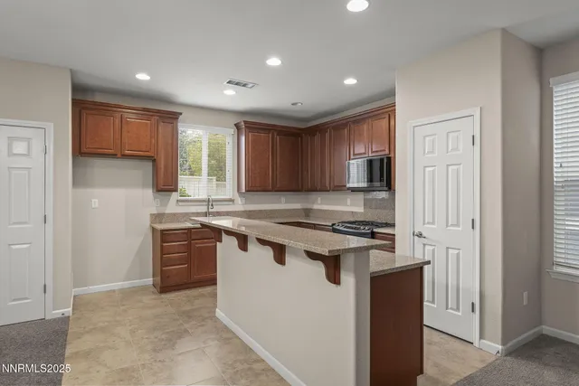 a kitchen with stainless steel appliances granite countertop a stove a refrigerator a sink dishwasher and a refrigerator with wooden cabinets