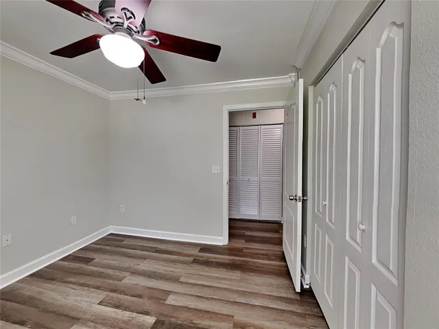 a view of a hallway with wooden floor and chandelier fan