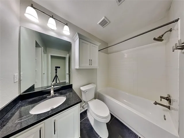 a bathroom with a granite countertop sink mirror toilet and bathtub