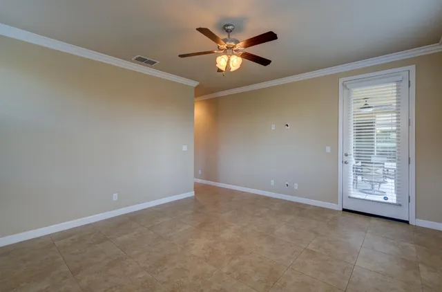 a view of an empty room with a ceiling fan and window