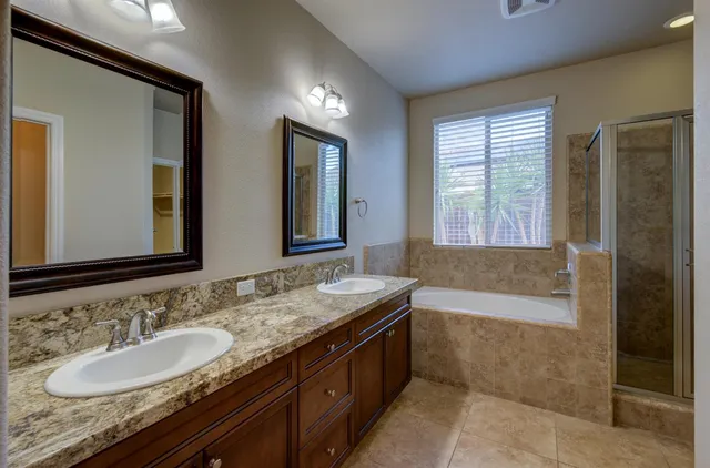 a bathroom with a granite countertop double vanity sink and a bathtub