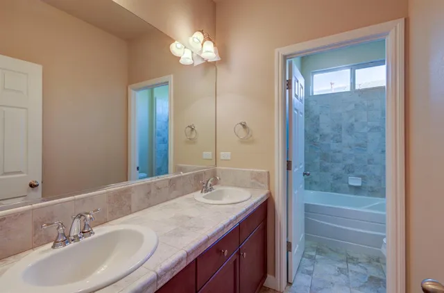 a bathroom with a sink double vanity granite tub and a mirror