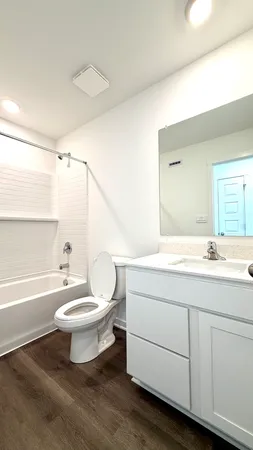 a bathroom with a double vanity sink a toilet a mirror and bathtub
