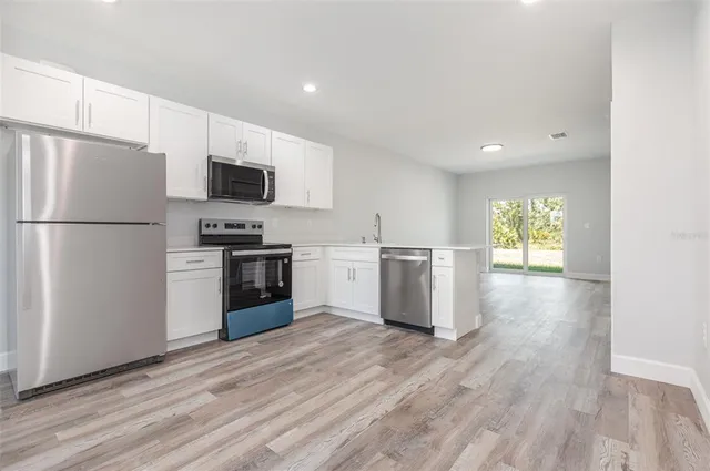 a kitchen with a refrigerator a stove top oven a sink and a hard wood floor