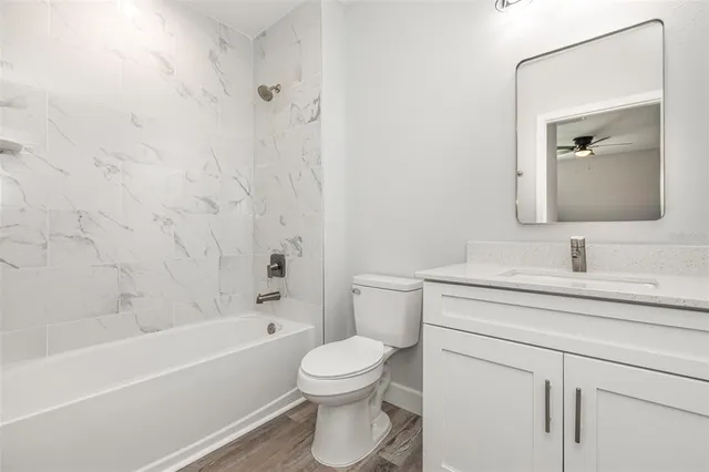 a bathroom with a toilet sink vanity tub and shower