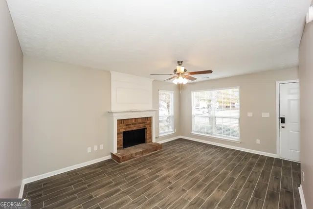 an empty room with wooden floor fireplace and windows