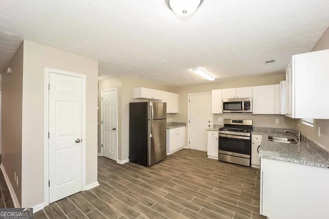 a kitchen with stainless steel appliances granite countertop a refrigerator and a stove top oven