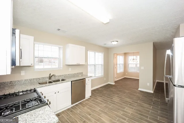 a large kitchen with stainless steel appliances granite countertop a stove a sink and a refrigerator