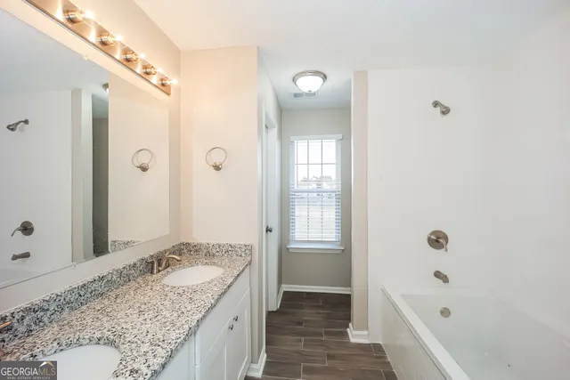 a bathroom with a granite countertop tub sink and mirror