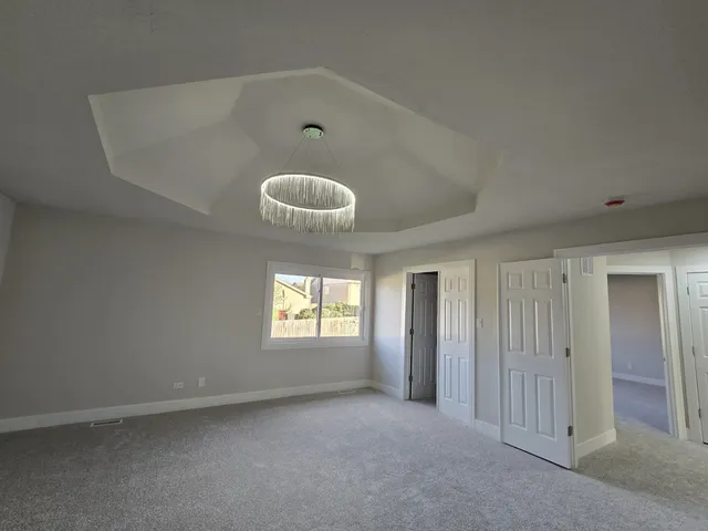 an empty room with windows and chandelier fan