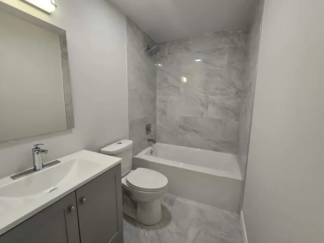 a bathroom with a bathtub shower sink mirror and toilet