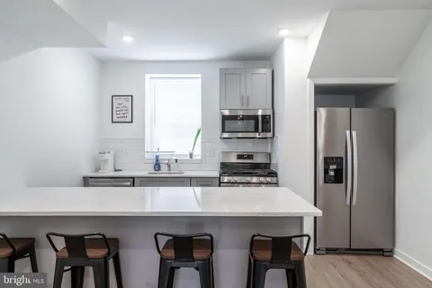 a kitchen with stainless steel appliances a table chairs refrigerator and sink