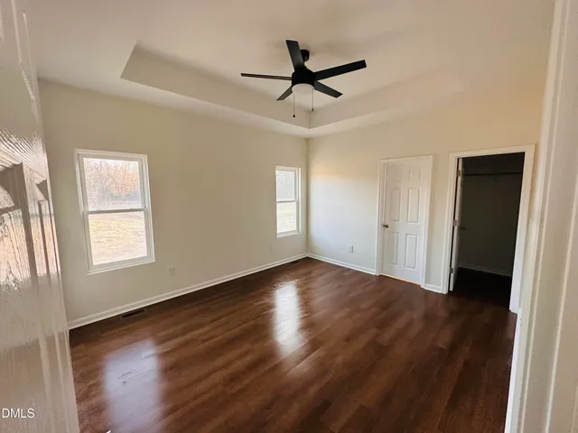 a view of empty room with wooden floor and fan