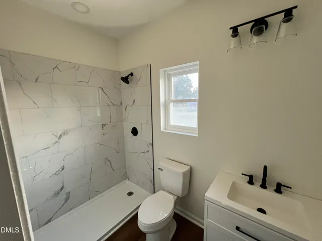 a bathroom with a toilet a sink a shower and mirror