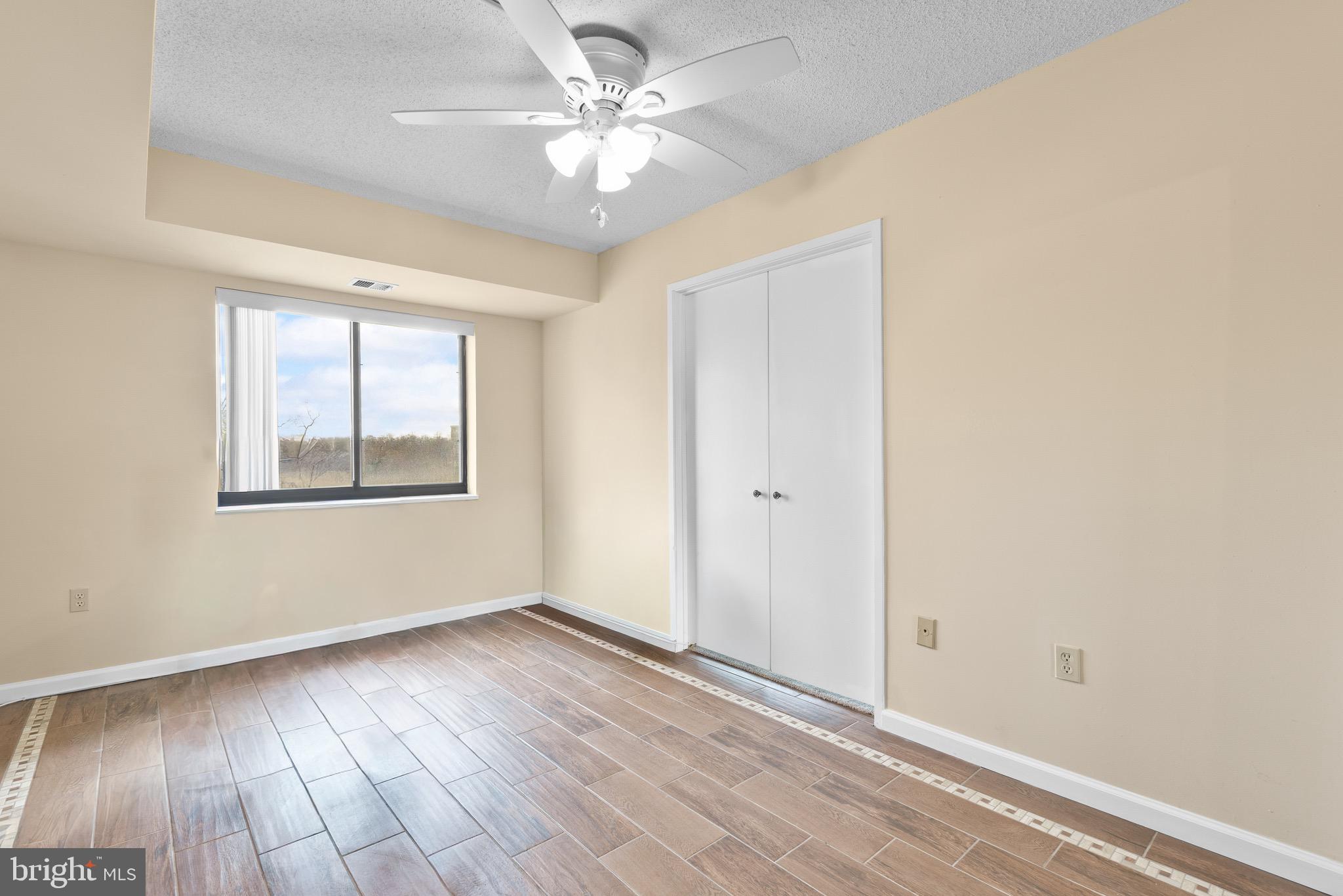 15115 Interlachen Drive, Unit 3607 Silver Spring, MD 20906 - Photo 17 of 37 an empty room with wooden floor chandelier fan and windows