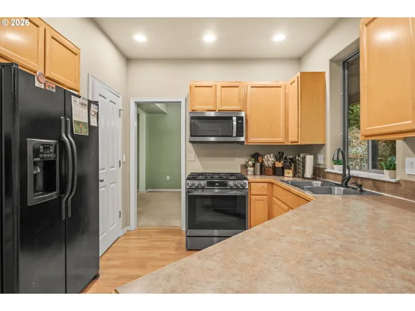 a kitchen with stainless steel appliances granite countertop a refrigerator a sink a stove and oven