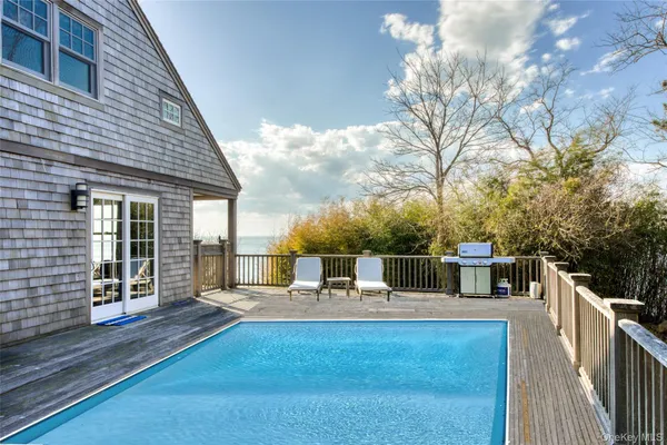 a view of house with deck outdoor seating and covered with trees