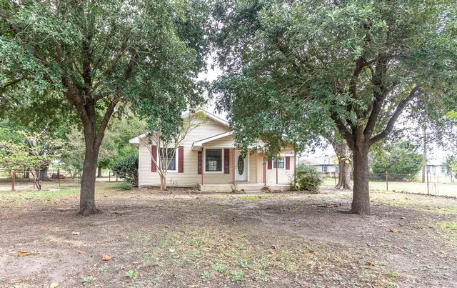 a front view of a house with a garden and trees