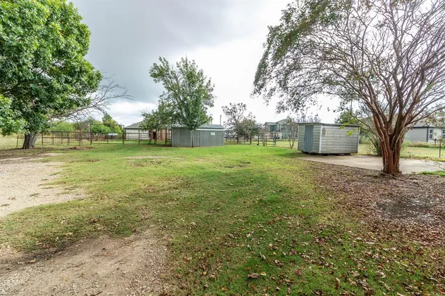 a view of a big yard with plants and large trees