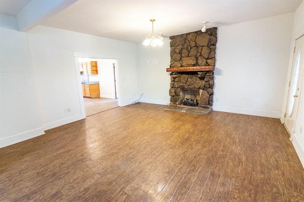 801 South Sutton Street Mabank, TX 75147 - Photo 7 of 26 an empty room with wooden floor fireplace and windows