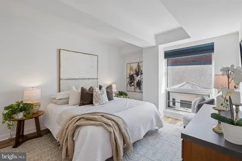 a bedroom with a bed and potted plants with the wooden floor