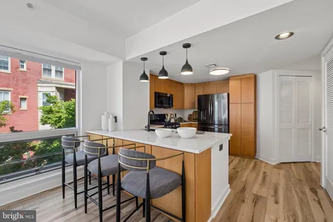 a kitchen with stainless steel appliances granite countertop a table chairs and a refrigerator