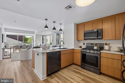 a kitchen with stainless steel appliances granite countertop a stove top oven a sink dishwasher and white cabinets with wooden floor