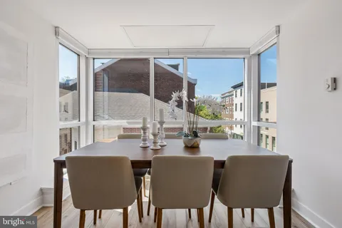 a dining room with furniture a large window and wooden floor