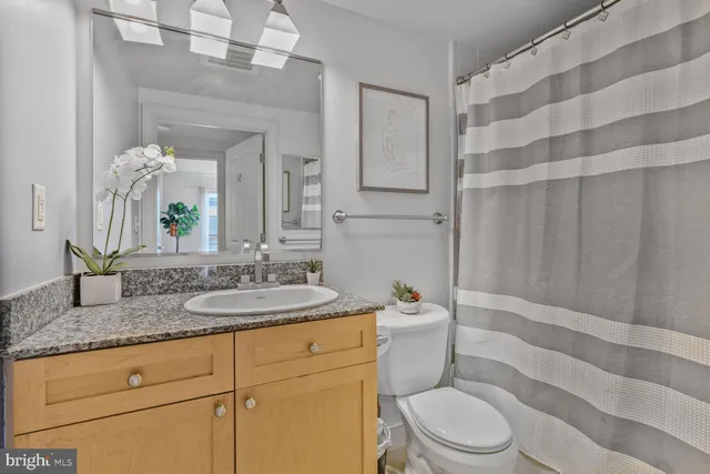 a bathroom with a granite countertop sink mirror vanity and toilet