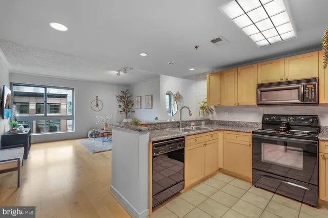 a kitchen with stainless steel appliances granite countertop a stove top oven a sink dishwasher a dining table and chairs with wooden floor