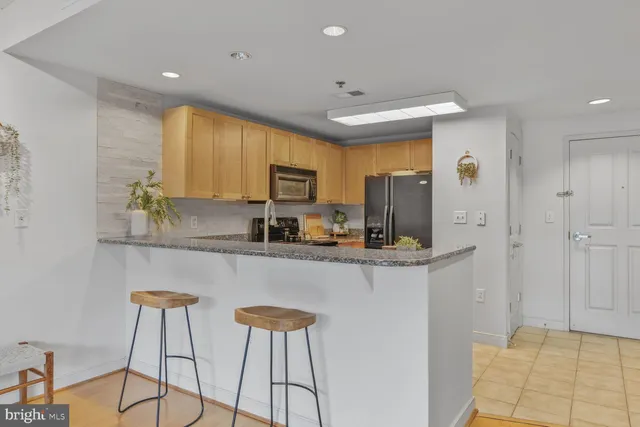 a kitchen with stainless steel appliances kitchen island granite countertop a refrigerator a stove a sink dishwasher and white cabinets with wooden floor