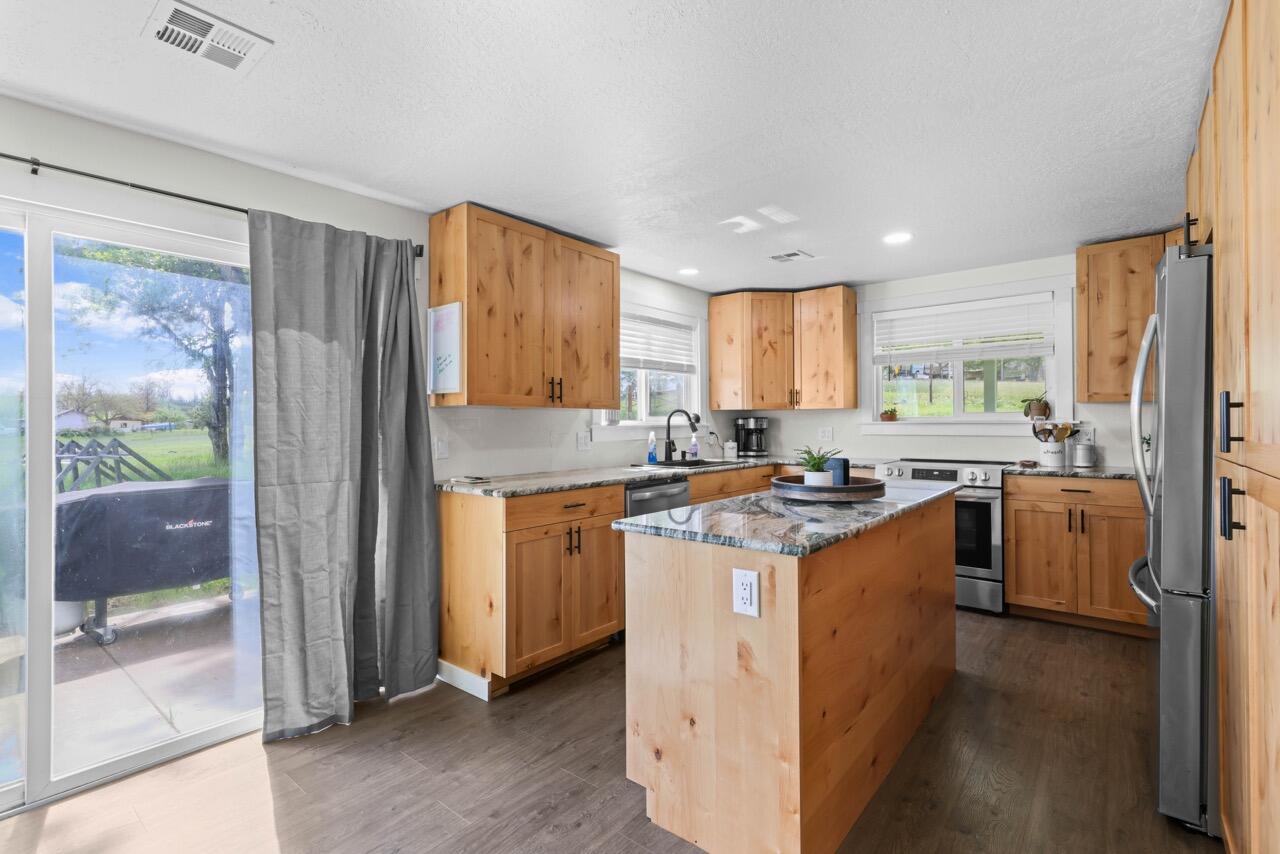 380 Greenleaf Drive Eagle Point, OR 97524 - Photo 17 of 31 a kitchen with stainless steel appliances granite countertop a stove a sink a refrigerator and a view of living room
