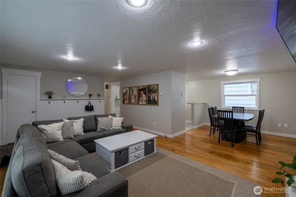 a living room with furniture and a dining table with wooden floor