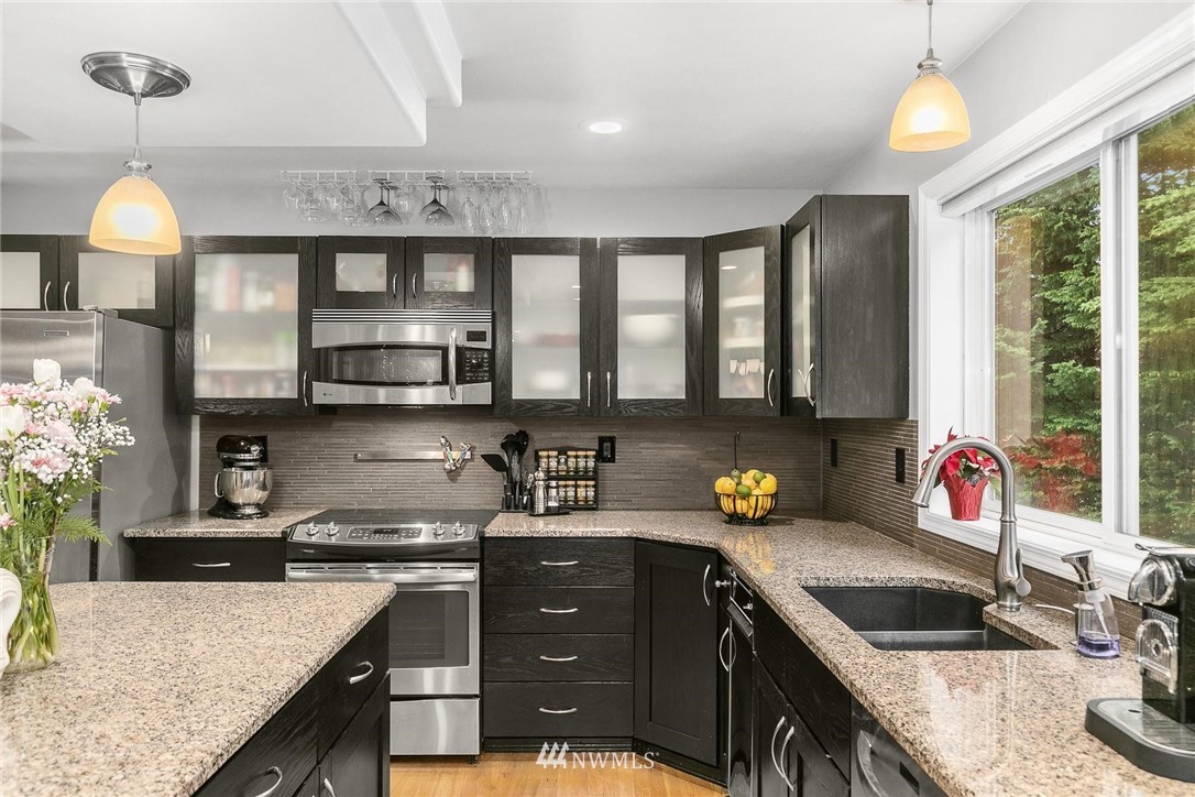 23809 Southeast 243rd Street Maple Valley, WA 98038 - Photo 11 of 40 a kitchen with stainless steel appliances granite countertop a sink stove and cabinets