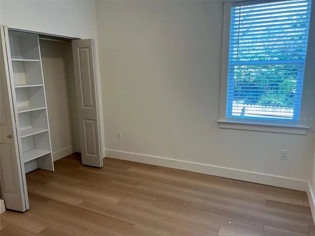 a view of an empty room with a window and wooden floor