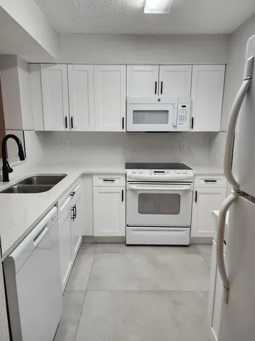 a white kitchen with a stove top oven sink and cabinets
