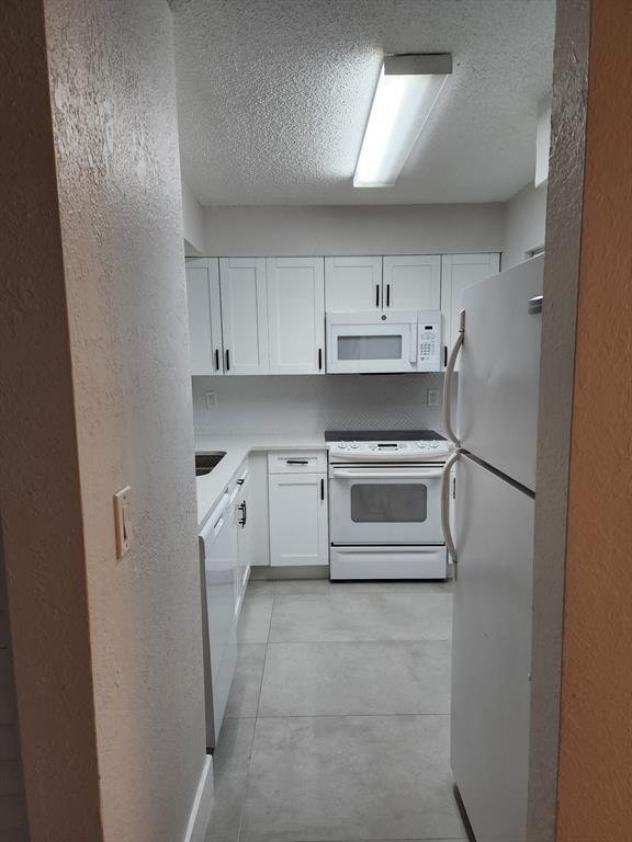 1229 Southwest 46th Avenue, Unit 405 Pompano Beach, FL 33069 - Photo 20 of 26 a kitchen with white cabinets and white appliances