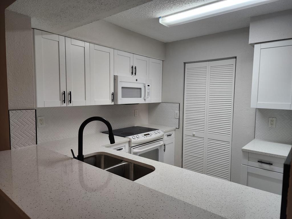 1229 Southwest 46th Avenue, Unit 405 Pompano Beach, FL 33069 - Photo 3 of 26 a kitchen with a sink a stove and cabinets