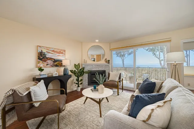 a living room with furniture a fireplace and a floor to ceiling window
