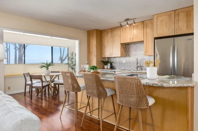 a kitchen with stainless steel appliances granite countertop a table chairs and a refrigerator