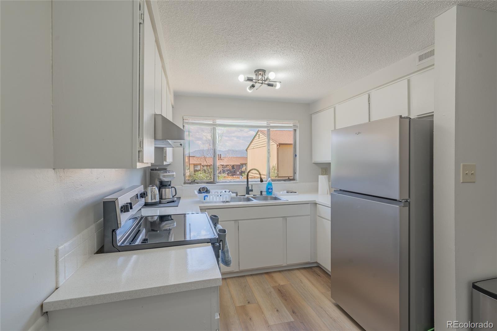 6727 Dale Road Colorado Springs, CO 80915 - Photo 7 of 18 a kitchen with a sink a refrigerator and cabinets
