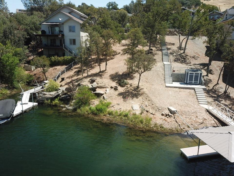 554 Sunrise Road Copperopolis, CA 95228 - Photo 3 of 20 a view of a lake with lawn chairs and large trees