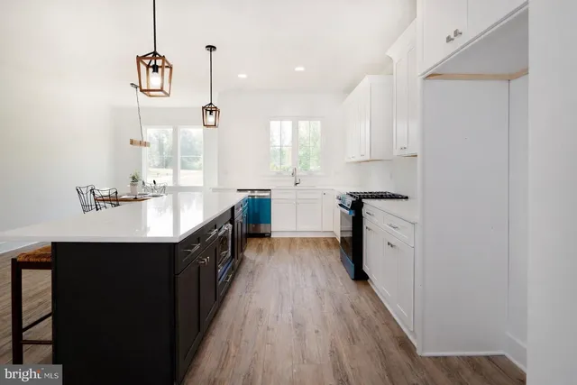 a kitchen with stainless steel appliances granite countertop a refrigerator a stove and a wooden floors