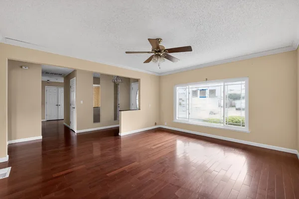 a view of an empty room with wooden floor and a window