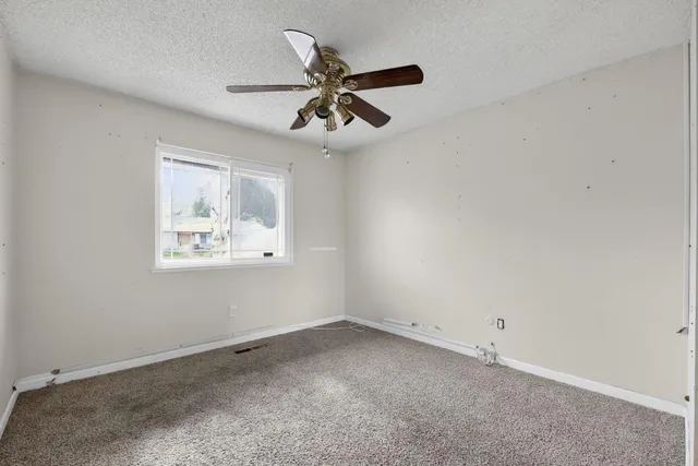 an empty room with a window and a ceiling fan