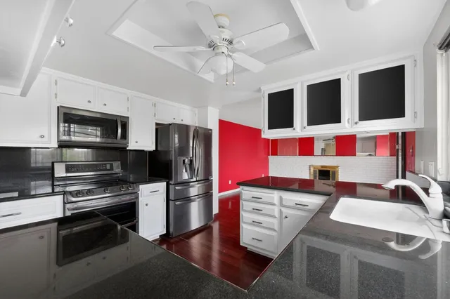 a kitchen with stainless steel appliances kitchen island granite countertop a sink and a refrigerator