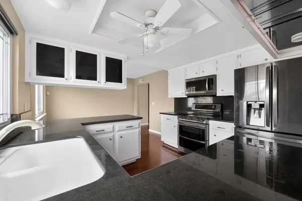 a kitchen with stainless steel appliances granite countertop a sink dishwasher stove and refrigerator with wooden floor