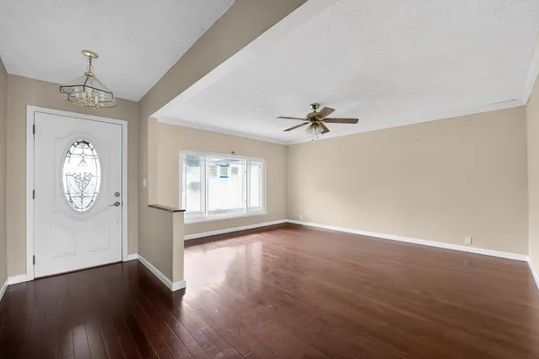 a view of an empty room with wooden floor and a window