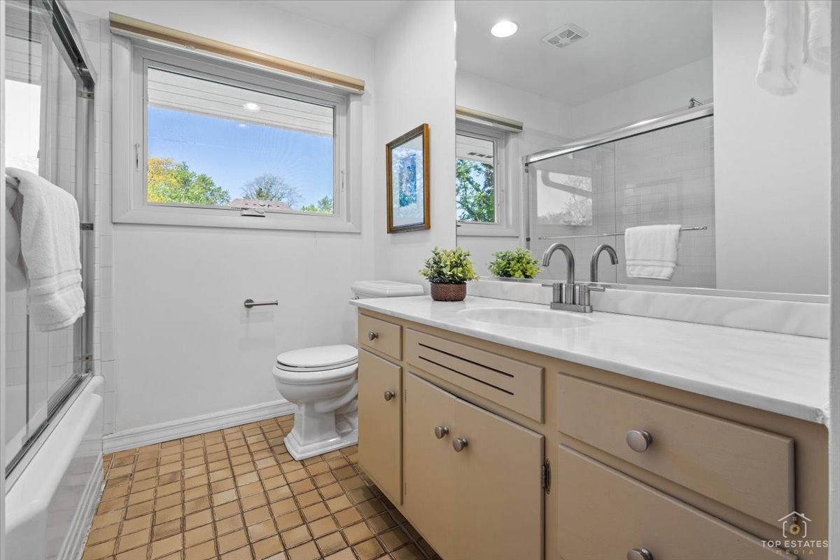 326 Charles Street Geneva, IL 60134 - Photo 20 of 33 a bathroom with a granite countertop toilet a sink a mirror and a window