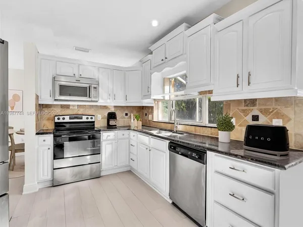 a kitchen with granite countertop white cabinets and stainless steel appliances